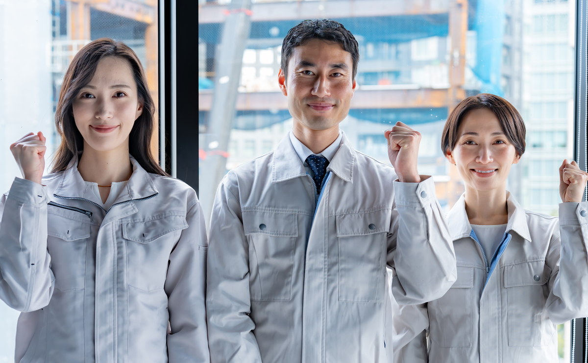 作業服姿の3人がガッツポーズをしているイメージ写真